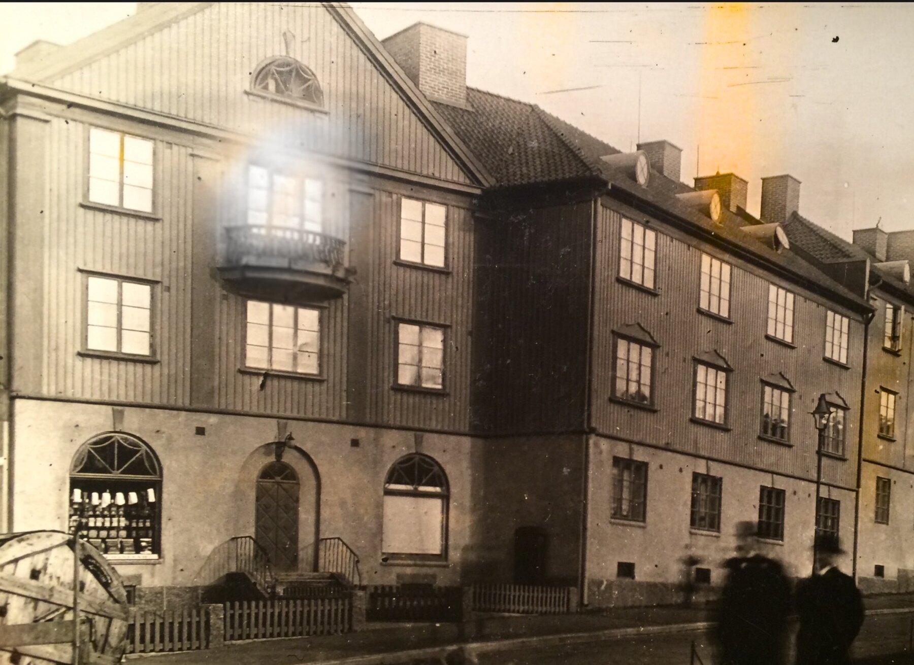 Stockholmsgatan – landshövdingehus med butik i stenvåningen, valvad port och svängd smidesbalkong. Odaterat foto.