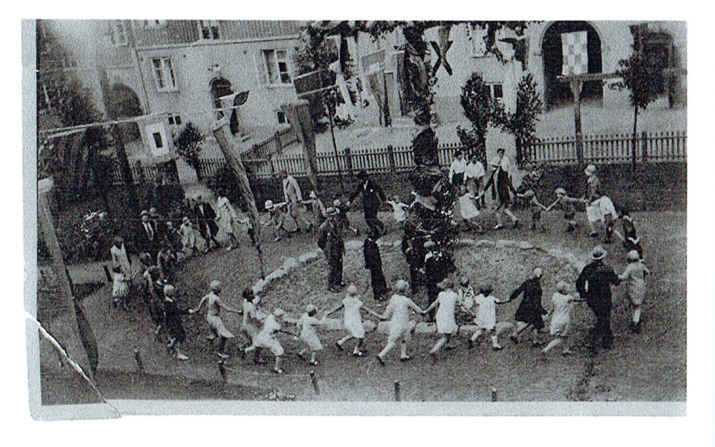 Barn dansar ringlek kring majstången på en gård, 1920–30-tal.