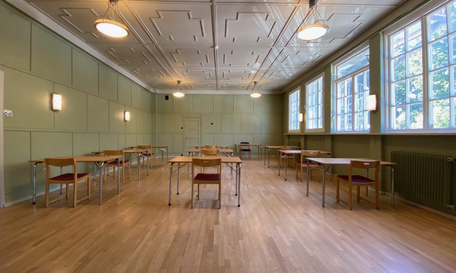 Konferensrum med dekorerat stuckaturtak och gröna panelväggar